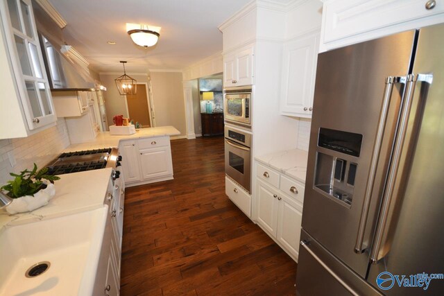 kitchen featuring tasteful backsplash, dark wood-type flooring, hanging light fixtures, appliances with stainless steel finishes, and white cabinets