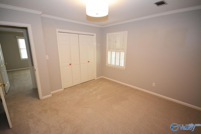 unfurnished bedroom featuring light carpet, crown molding, and a closet