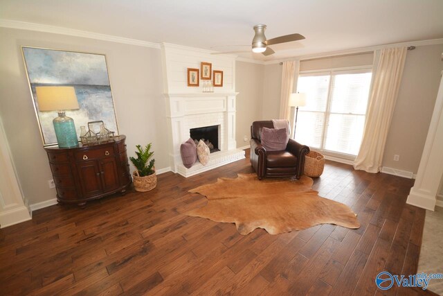 living area with crown molding, ceiling fan, dark hardwood / wood-style flooring, and a fireplace