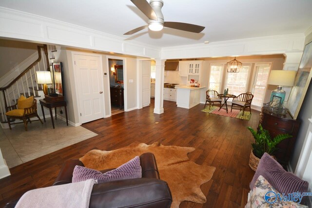 living room featuring crown molding, ornate columns, ceiling fan, and dark hardwood / wood-style floors