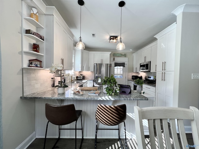 kitchen featuring tasteful backsplash, appliances with stainless steel finishes, a peninsula, and a sink