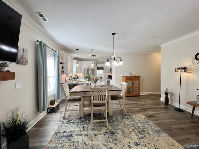 dining space with visible vents, crown molding, dark wood-type flooring, and an inviting chandelier