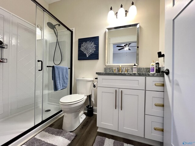 bathroom with wood finished floors, toilet, a stall shower, and vanity