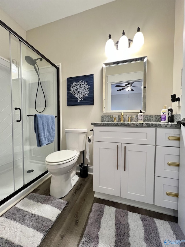 bathroom featuring a shower stall, baseboards, toilet, wood finished floors, and vanity