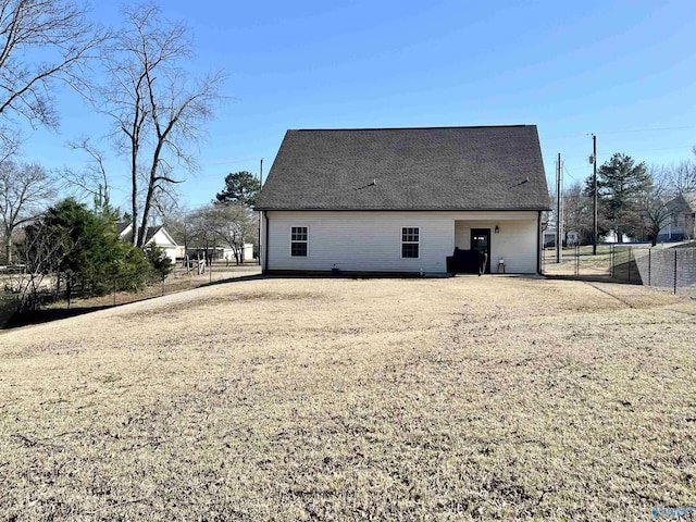 rear view of property with a shingled roof and fence