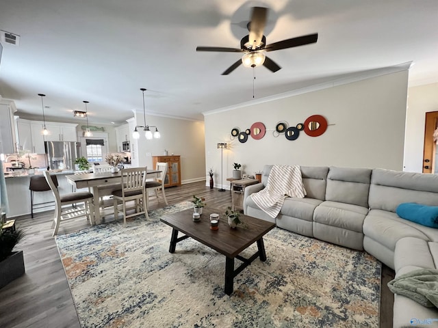 living room featuring visible vents, crown molding, baseboards, ceiling fan, and wood finished floors