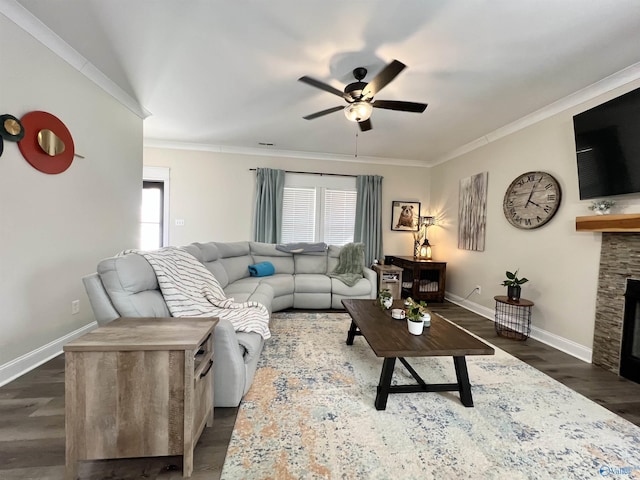 living area with a ceiling fan, baseboards, a fireplace, dark wood-style flooring, and ornamental molding