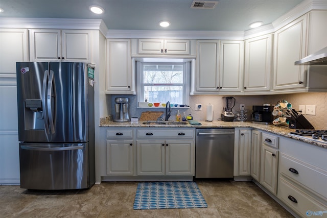 kitchen with white cabinetry, appliances with stainless steel finishes, tasteful backsplash, light stone counters, and sink