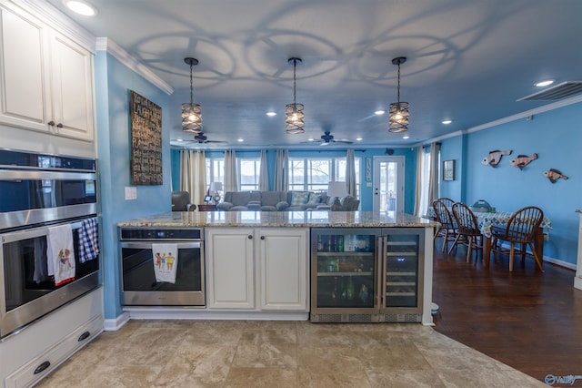 kitchen with stainless steel double oven, beverage cooler, decorative light fixtures, white cabinetry, and crown molding