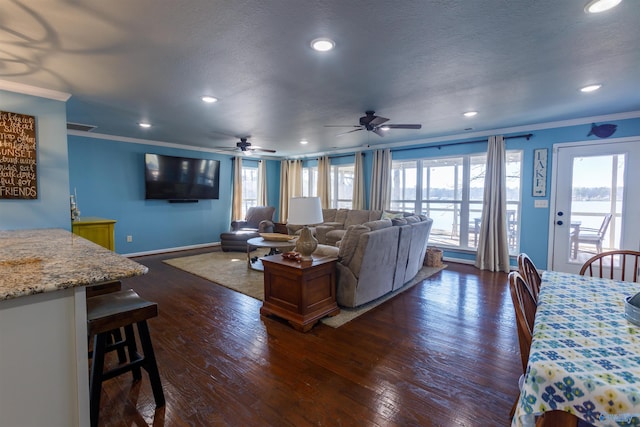 living room featuring ceiling fan, a textured ceiling, dark hardwood / wood-style floors, and ornamental molding