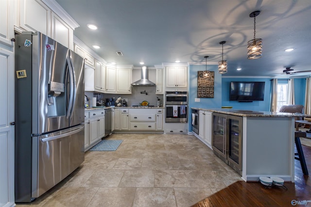 kitchen featuring appliances with stainless steel finishes, wall chimney range hood, white cabinetry, a kitchen breakfast bar, and kitchen peninsula