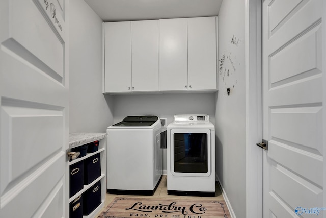 clothes washing area featuring light wood-style floors, cabinet space, baseboards, and separate washer and dryer