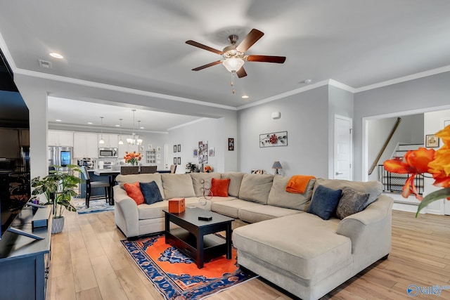 living room with light wood finished floors, stairs, crown molding, and ceiling fan with notable chandelier