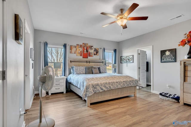 bedroom with visible vents, multiple windows, light wood-style flooring, and baseboards