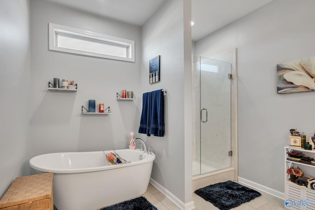 full bath featuring a stall shower, baseboards, a freestanding tub, and tile patterned floors