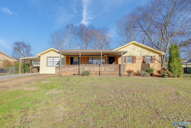 ranch-style home with an attached carport, covered porch, concrete driveway, and a front yard