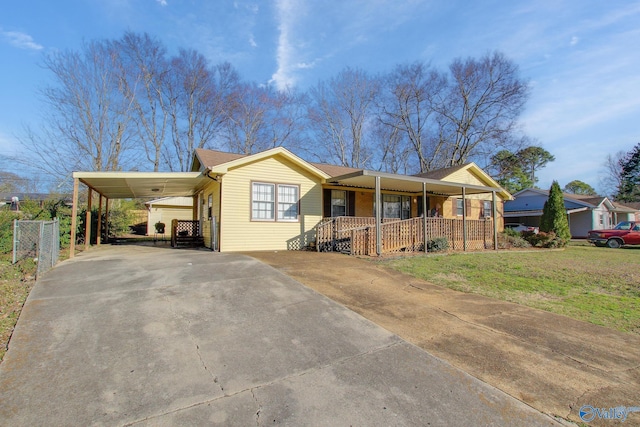 ranch-style home featuring an attached carport, covered porch, driveway, and a front lawn