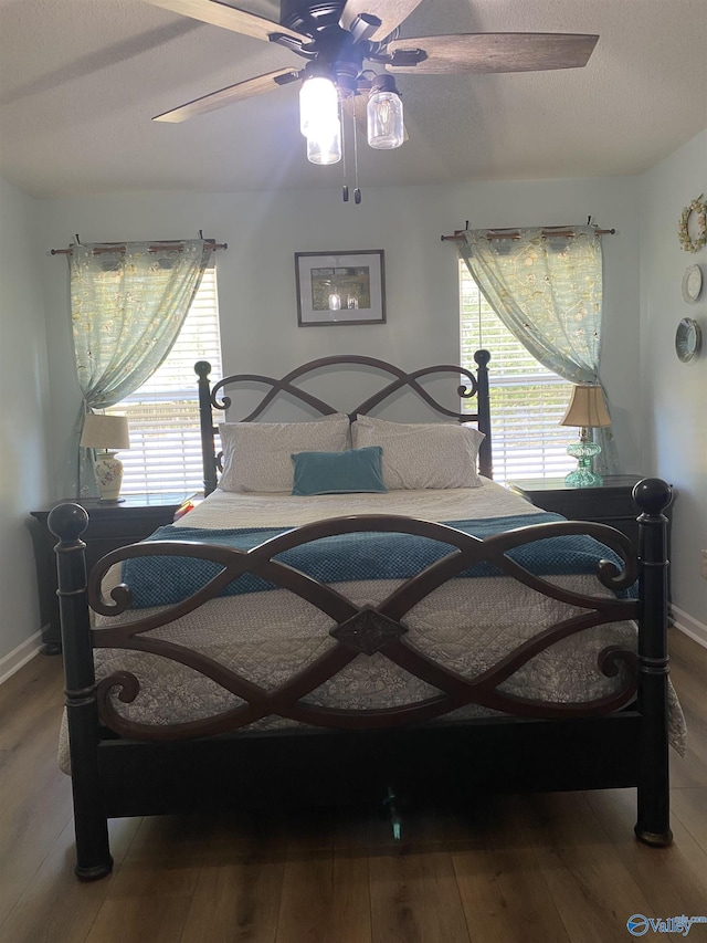bedroom featuring wood finished floors, baseboards, and a ceiling fan