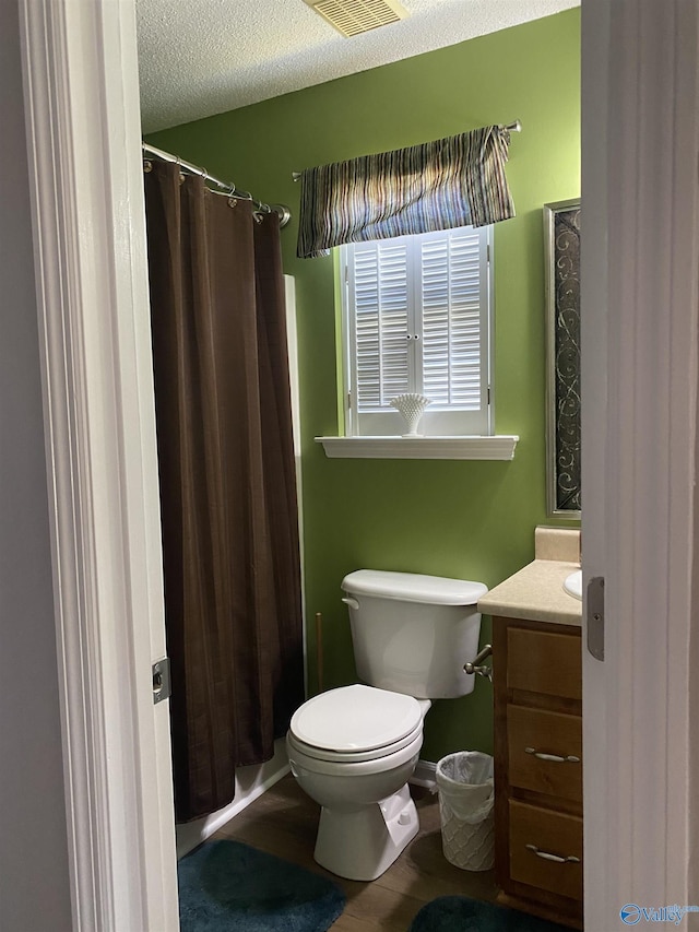 bathroom featuring a textured ceiling, vanity, toilet, wood finished floors, and a shower with shower curtain