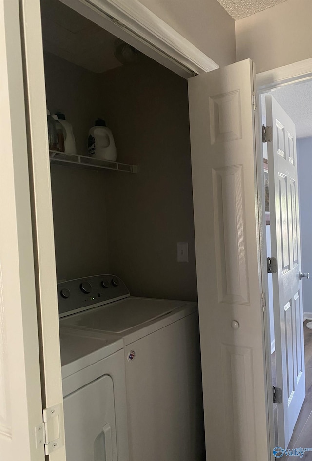 washroom featuring washer and clothes dryer, laundry area, and a textured ceiling