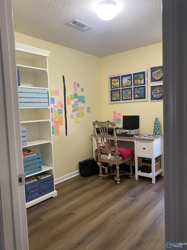 office area featuring visible vents, baseboards, wood finished floors, and a textured ceiling