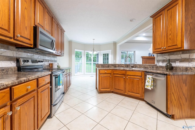 2115 James Dr, Southside, AL 35907 - kitchen featuring appliances with stainless steel finishes, a sink, brown cabinetry, dark countertops, and crown molding