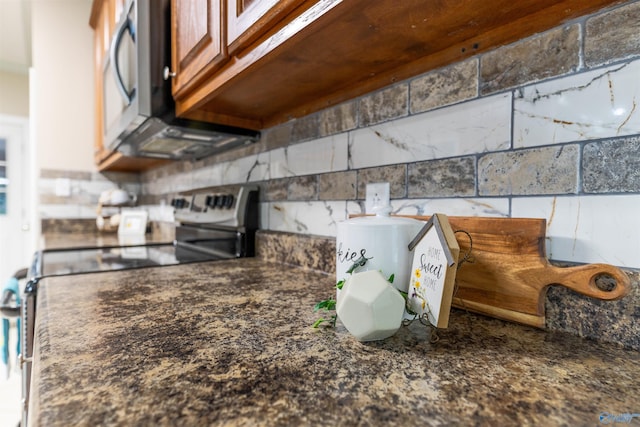 2115 James Dr, Southside, AL 35907 - kitchen view of stainless steel appliances, decorative backsplash, dark countertops, and brown cabinets