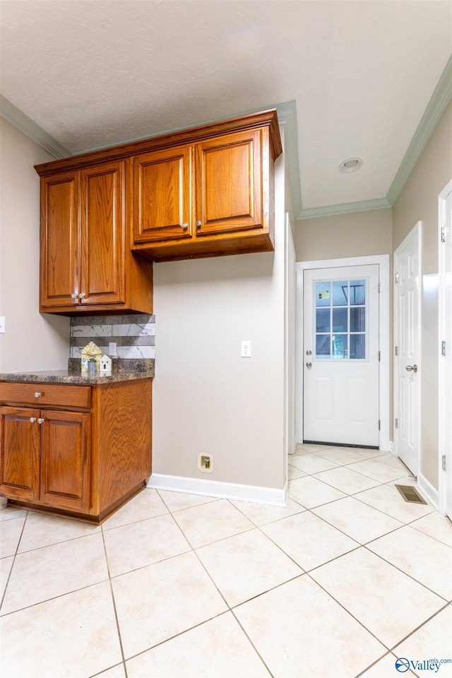 2115 James Dr, Southside, AL 35907 - kitchen with brown cabinets, ornamental molding, light tile patterned floors, decorative backsplash, and baseboards