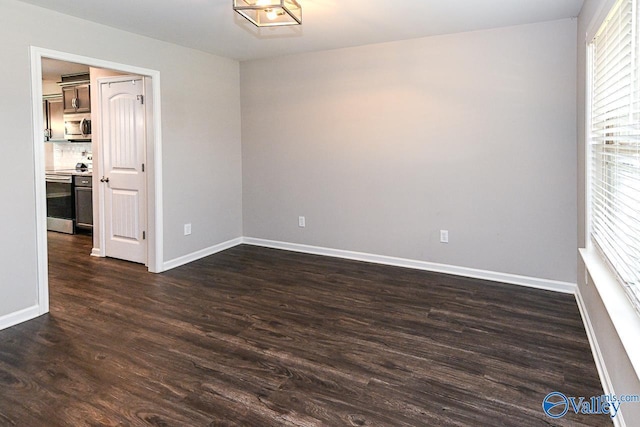 empty room featuring baseboards and dark wood-style floors