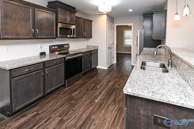 kitchen featuring dark brown cabinetry, tasteful backsplash, a sink, dark wood finished floors, and appliances with stainless steel finishes