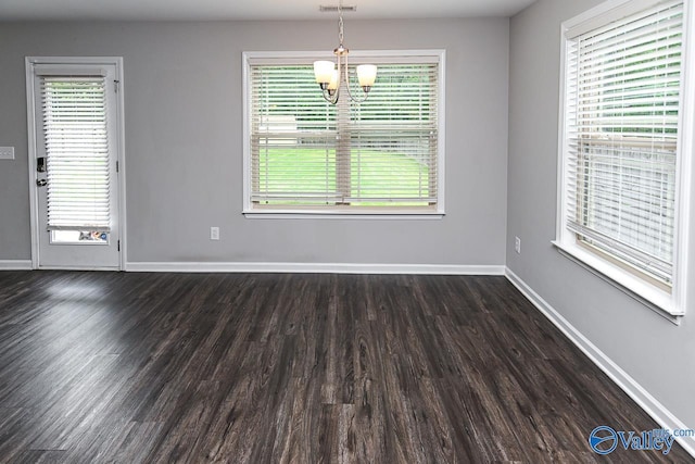 spare room with an inviting chandelier, baseboards, dark wood-style floors, and visible vents