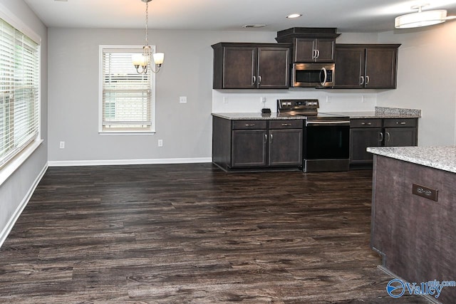 kitchen featuring dark brown cabinetry, dark wood-style flooring, appliances with stainless steel finishes, baseboards, and a notable chandelier