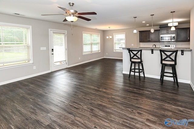 living room with baseboards, ceiling fan with notable chandelier, dark wood-style flooring, and visible vents