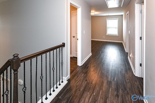 corridor featuring baseboards, an upstairs landing, and wood finished floors