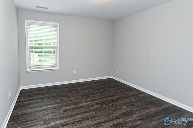 spare room featuring dark wood-style flooring, baseboards, and visible vents