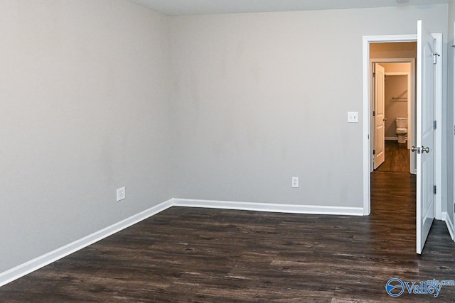 unfurnished room with baseboards and dark wood-style floors