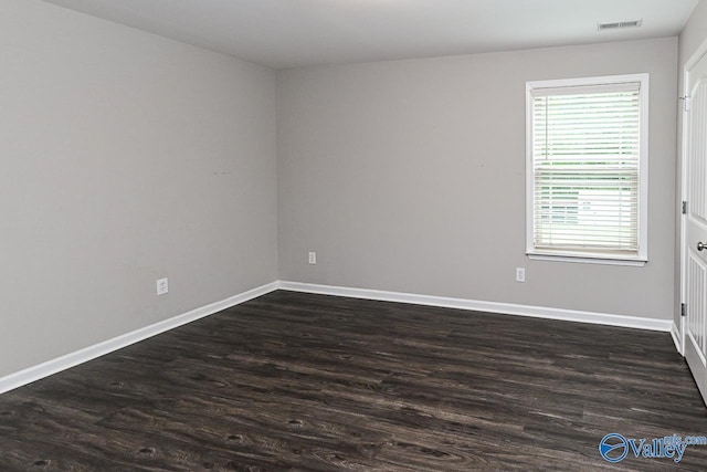 unfurnished room featuring baseboards, visible vents, and dark wood-type flooring