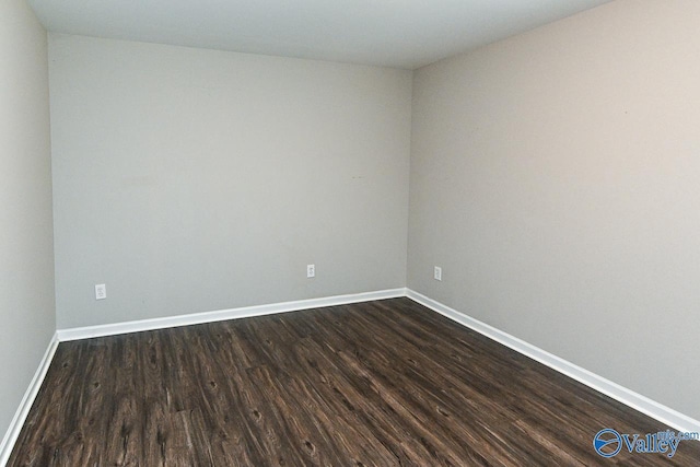spare room with baseboards and dark wood-style flooring