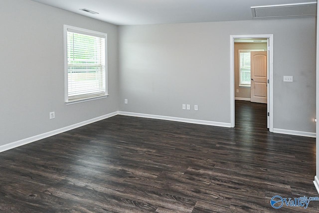 spare room with baseboards, dark wood-style floors, and visible vents