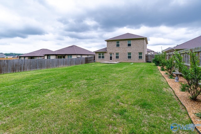 rear view of property featuring a fenced backyard and a yard