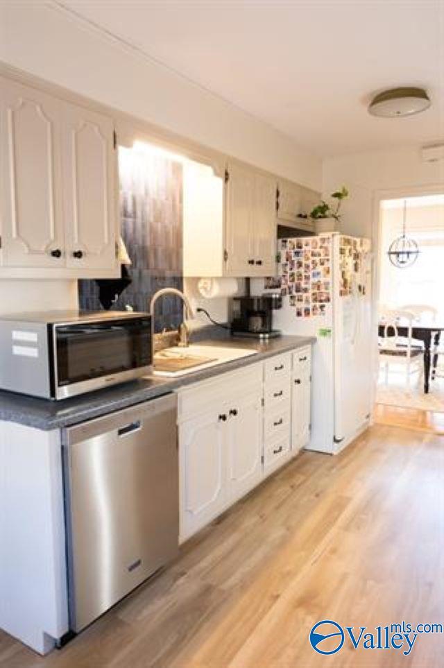 kitchen featuring white cabinets, stainless steel appliances, light hardwood / wood-style floors, and sink