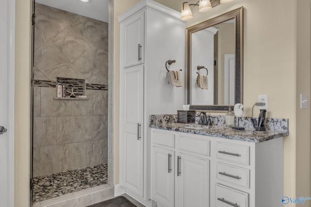 bathroom featuring tile patterned flooring, vanity, and tiled shower