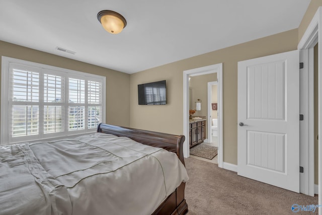 bedroom featuring light carpet and ensuite bath