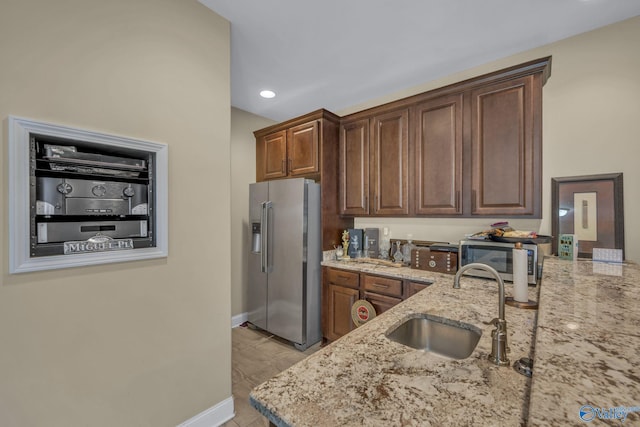 kitchen featuring light stone counters, sink, and stainless steel appliances