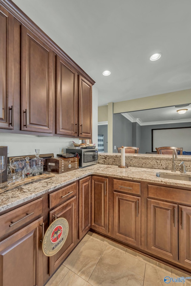 kitchen with light stone counters, sink, light tile patterned flooring, and ornamental molding