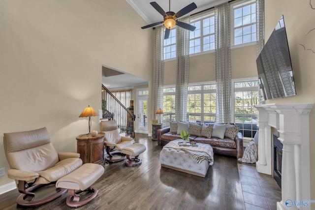 living room with dark hardwood / wood-style floors, ceiling fan, a towering ceiling, and crown molding