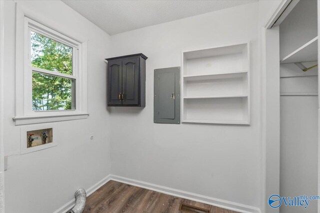 washroom with a textured ceiling, dark hardwood / wood-style flooring, hookup for a washing machine, cabinets, and electric panel