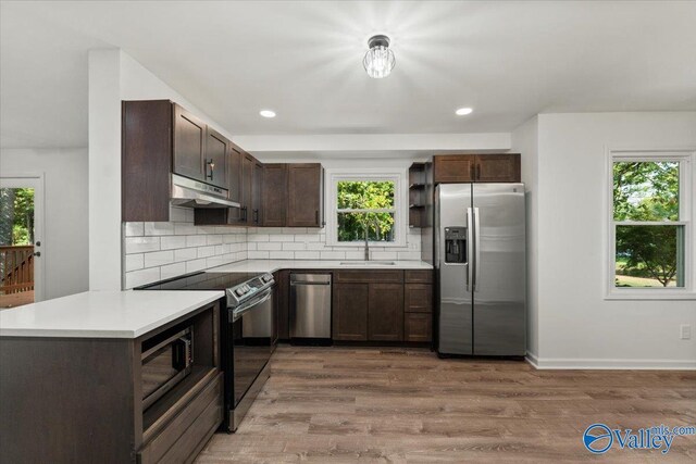 kitchen featuring dark brown cabinets, backsplash, appliances with stainless steel finishes, and hardwood / wood-style flooring