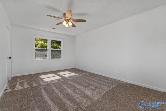 unfurnished room with dark carpet, ceiling fan, and a textured ceiling