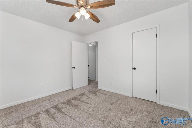 unfurnished bedroom featuring a textured ceiling, ceiling fan, and carpet flooring